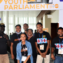 Five people stand under a sign reading 'Youth Parliament'.