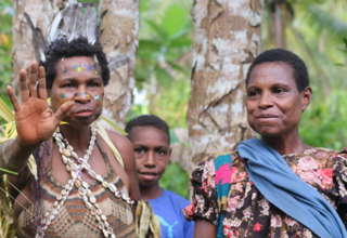 Two women stand side by side, one in traditional dress from the Sepik Region.
