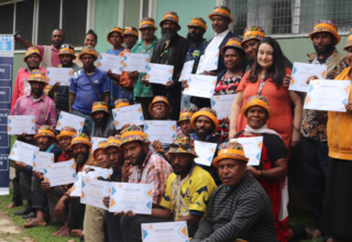 Group of 30 people holding certificates and looking to camera.