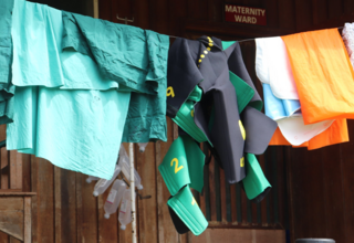 A green shock garment hangs on a washing line with linens from maternity ward.