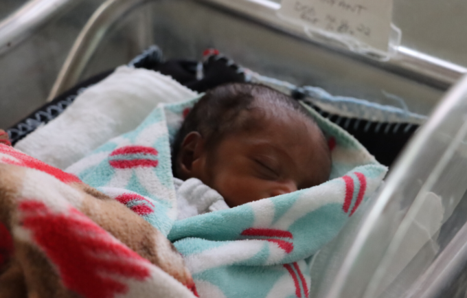 A baby sleeps in a neonatal care facility.