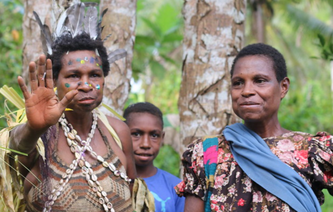 Two women stand side by side, one in traditional dress from the Sepik Region.