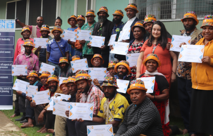 Group of 30 people holding certificates and looking to camera.