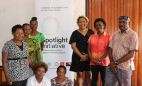 Seven people stand in front of standing banner reading ' Spotlight Initiative'.