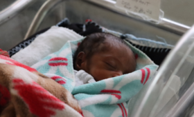 A baby sleeps in a neonatal care facility.