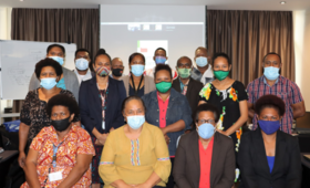Group of people in masks pose for photo at small workshop event.