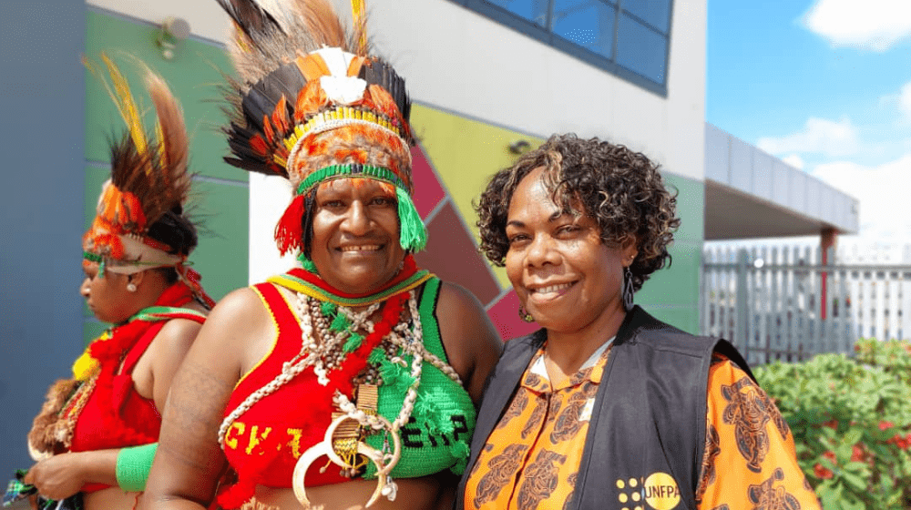 Woman dressed in traditional Eastern Highlands dress standing beside woman in UNFPA shirt.