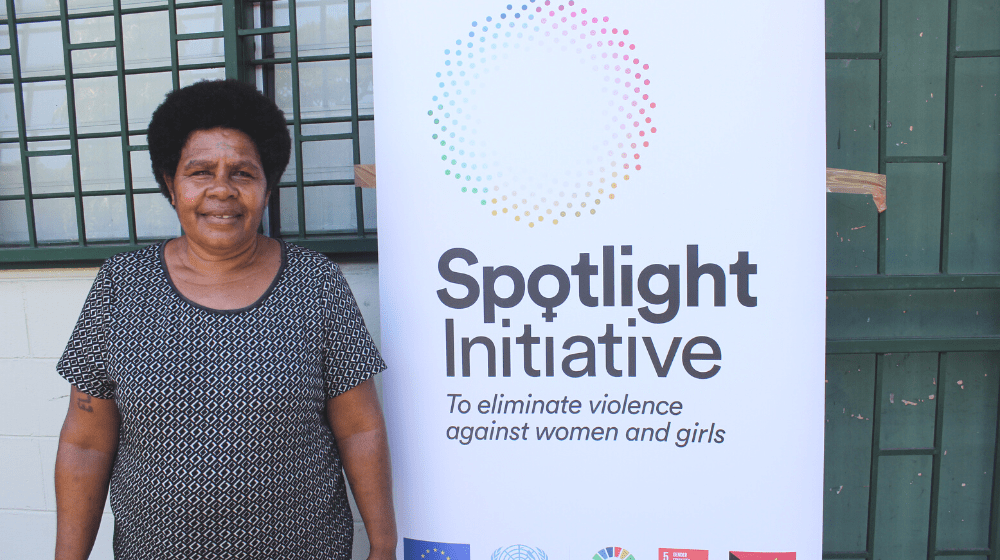 A woman stands next to a white banner with 'Spotlight' written in black.