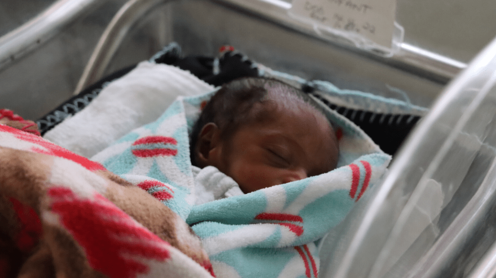 A baby sleeps in a neonatal care facility.