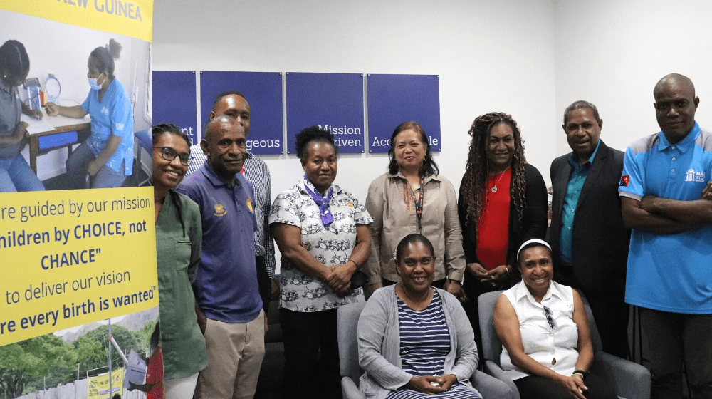 Group of people pose for photo with standing banner for Marie Stopes behind.