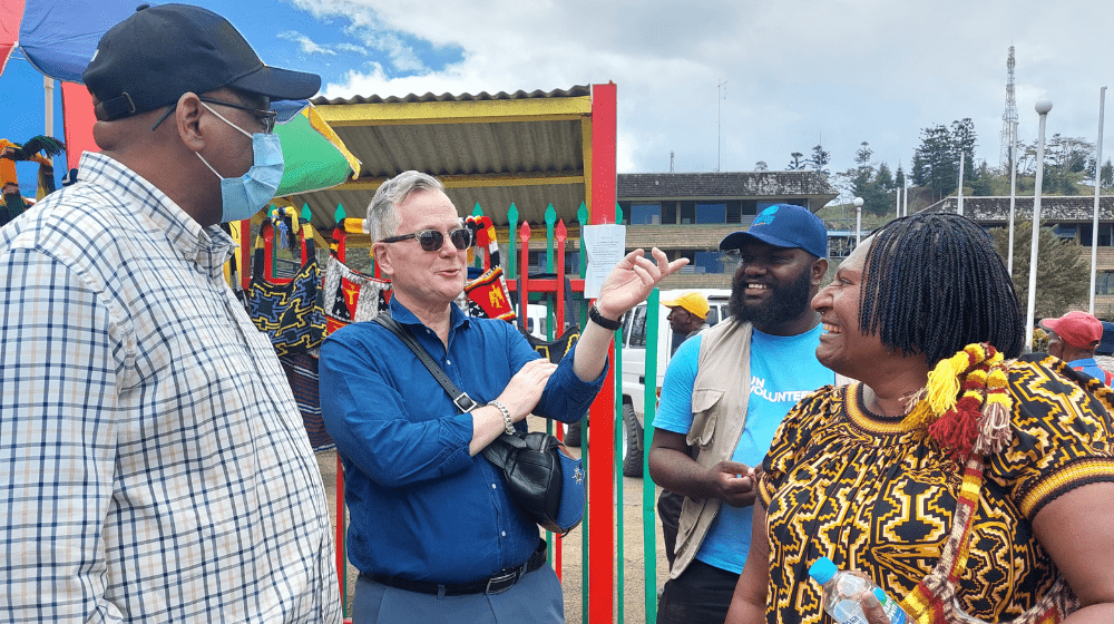 Four people stand talking in a market.