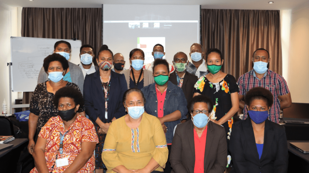 Group of people in masks pose for photo at small workshop event.