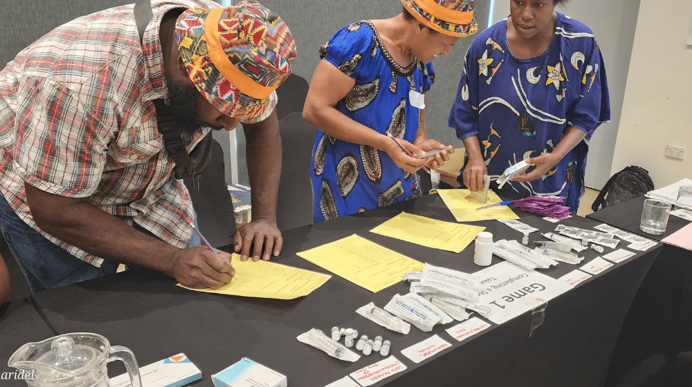 Three people standing over a desk working with health supply orders. 