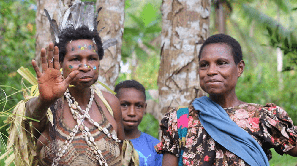 Two women stand side by side, one in traditional dress from the Sepik Region.