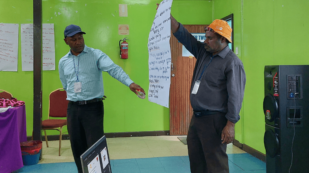 Man standing pointing at a workshop poster. 