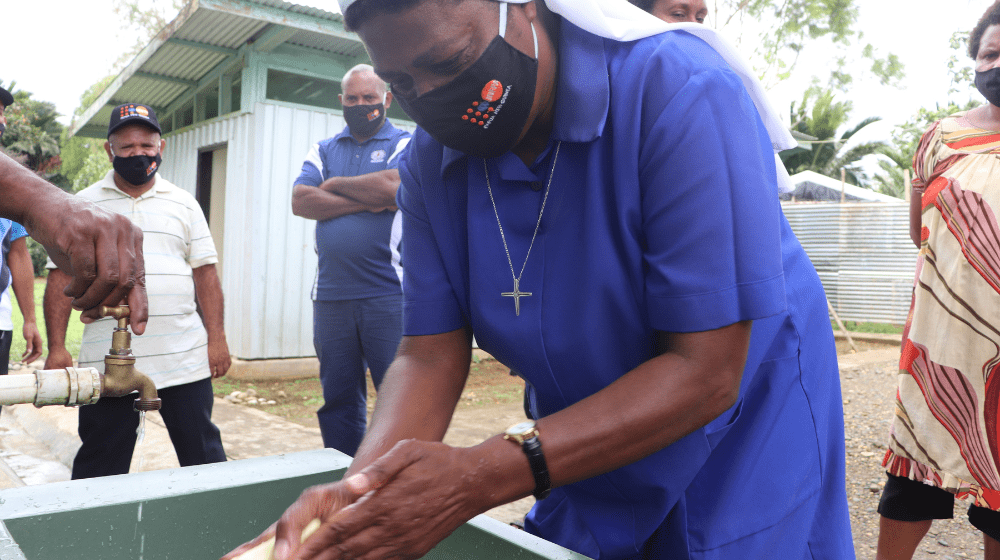 Nun washing hands wearing UNFPA face mask. 