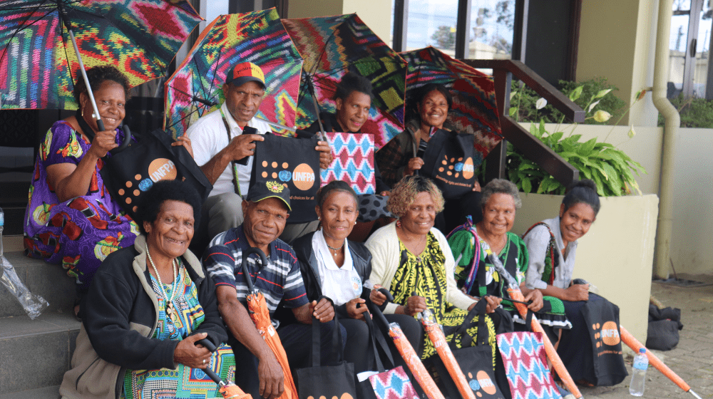 A gorup of ten people sit on stairs looking to the camera.