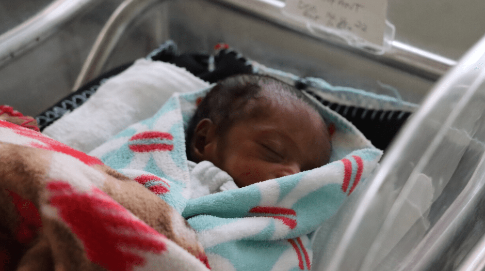 A newborn baby sleeps wrapped in a wrapped in a blanket. 