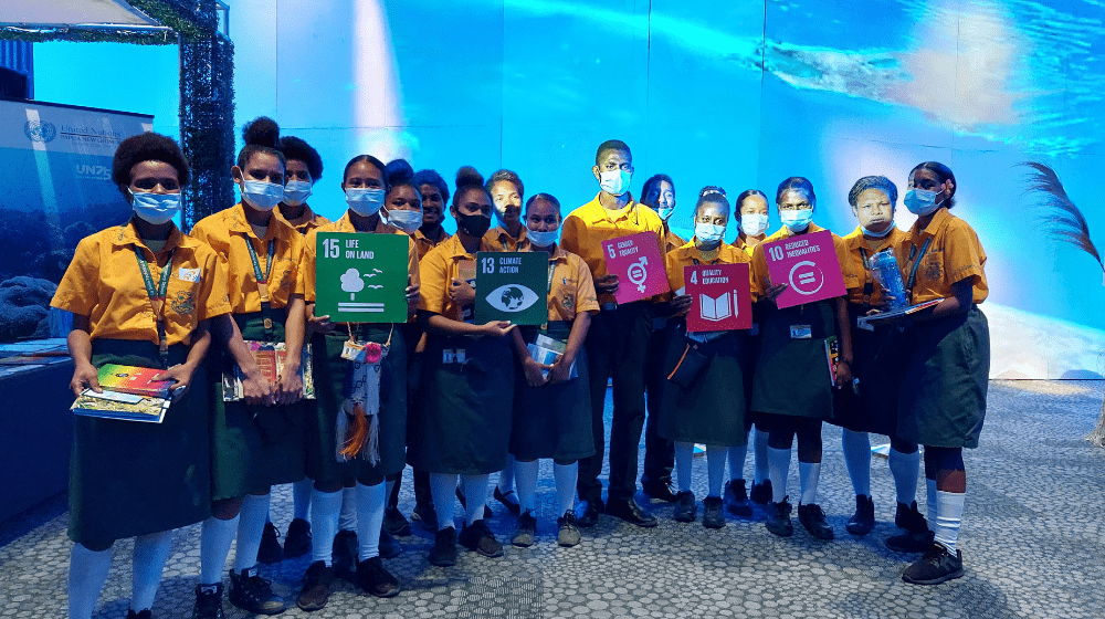 20 students pose for photo with SDG cards.