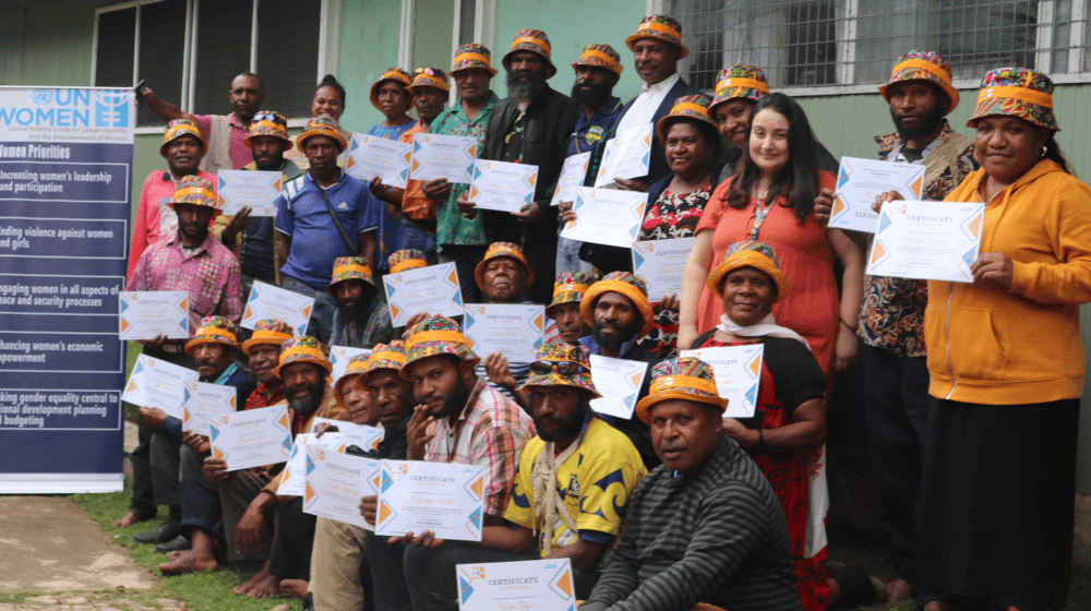 Group of 30 people holding certificates and looking to camera.