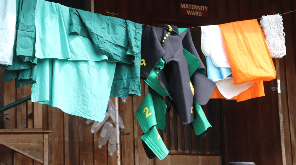 A green shock garment hangs on a washing line with linens from maternity ward.