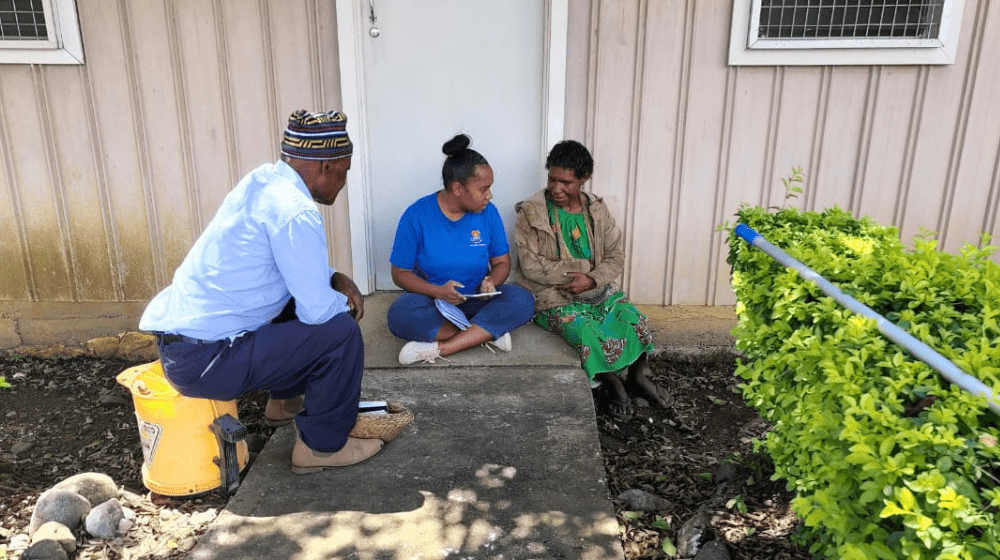 Two women are sitting on a front step, one asking questions. 