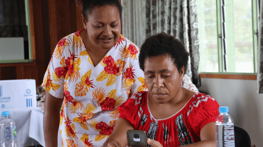 One woman observes other woman using mobile phone.